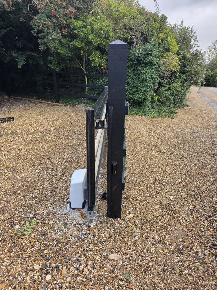 Hydraulic ram automation fitted to a black swing gate